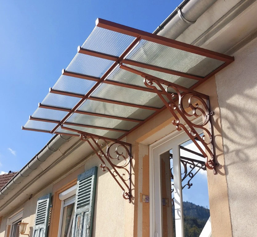 Extérieur résidentiel avec auvent décoratif en métal rouge installé au-dessus d'une entrée