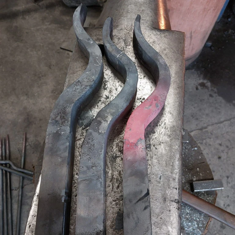Atelier de forge intérieur, artisan manipulant une pièce métallique chauffée au rouge incandescent avec des pinces de forgeron