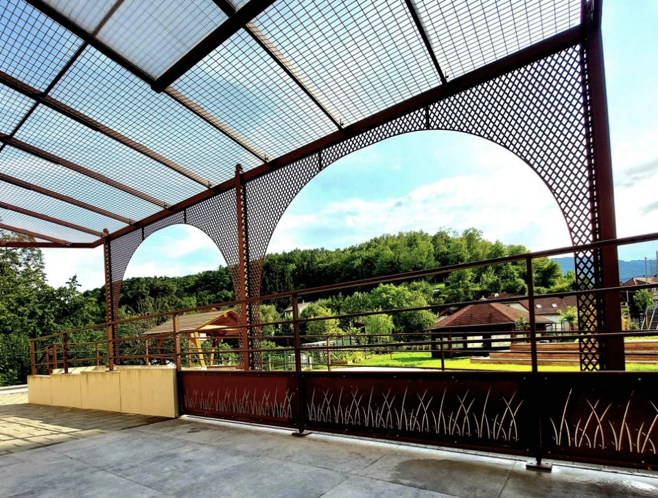 Terrasse extérieure branchée structure ombragée de pergola en bois foncé, auvent et toit-terrasse, table à manger blanche, chaises blanches, grill en métal entouré de paysages dans un quartier américain de luxe