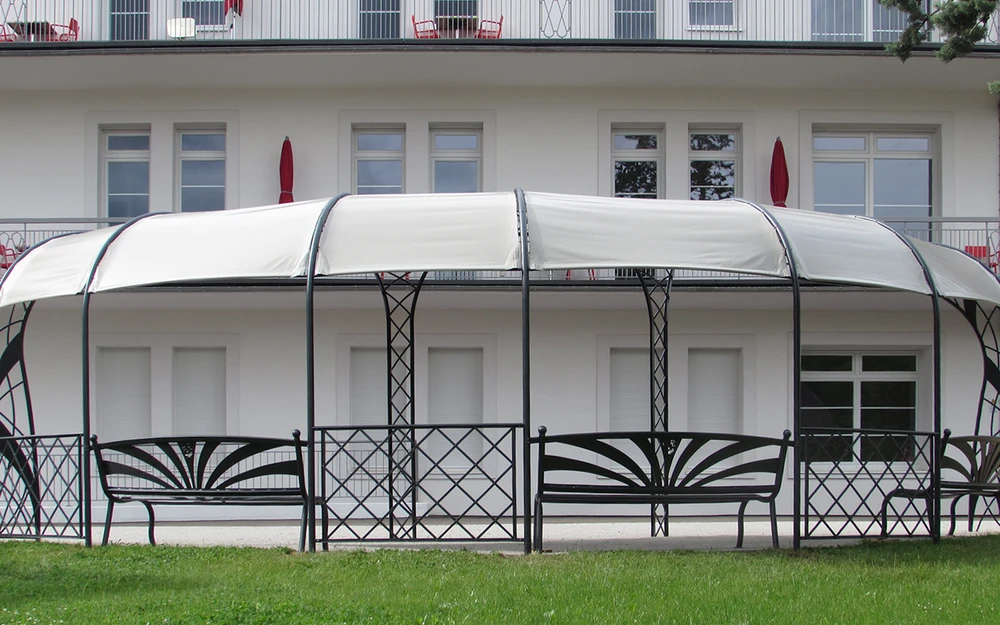 Portail en fer forgé blanc artistique avec motifs végétaux ondulants, installé entre piliers maçonnés