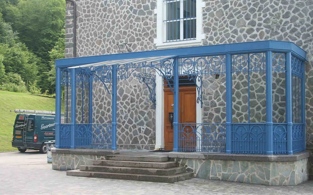 Entrée principale d'une maison moderne avec marquise en verre et structure métallique noire