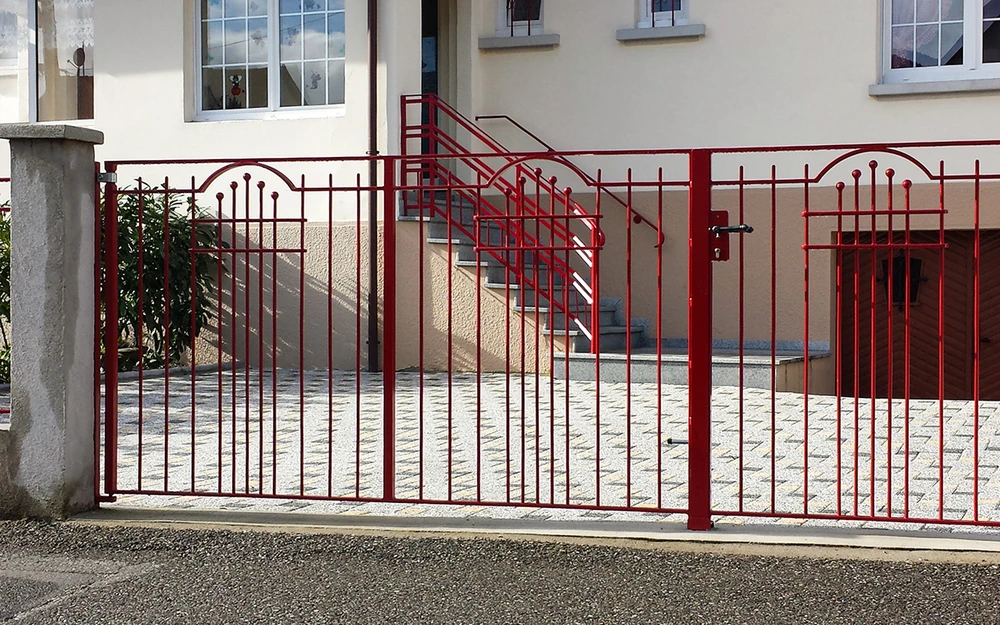 Portail en fer forgé blanc artistique avec motifs végétaux ondulants, installé entre piliers maçonnés