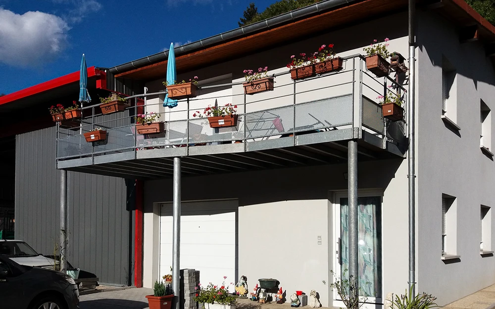 Portail en fer forgé blanc artistique avec motifs végétaux ondulants, installé entre piliers maçonnés